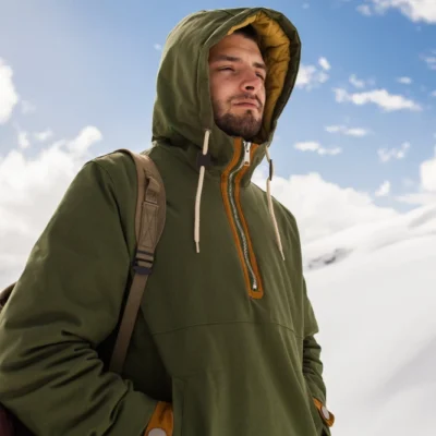 Excursionista con sistema de tres capas en alta montaña nevada, ropa técnica para clima extremo