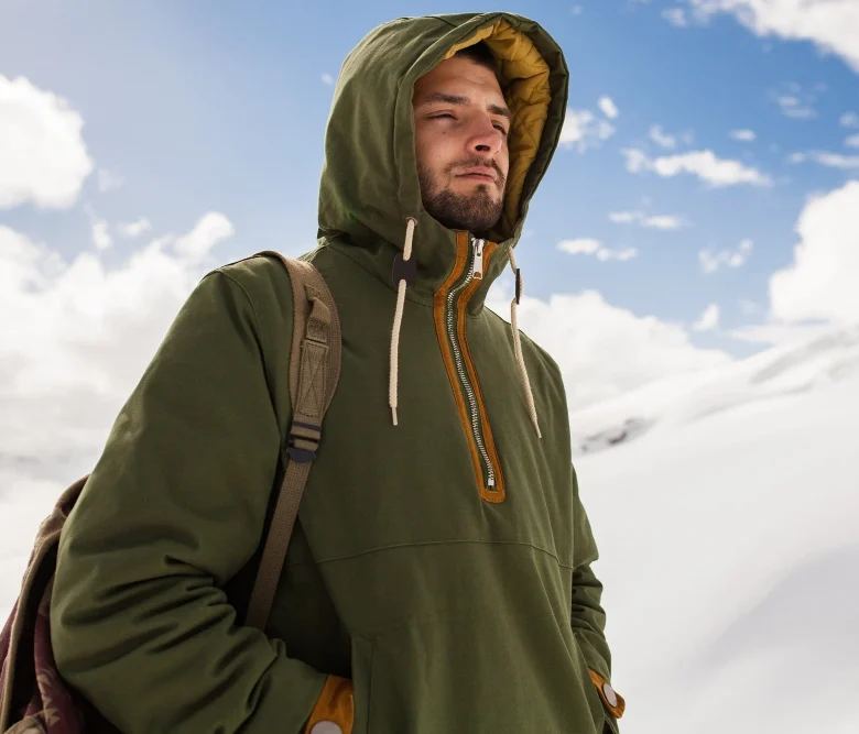 Excursionista con sistema de tres capas en alta montaña nevada, ropa técnica para clima extremo